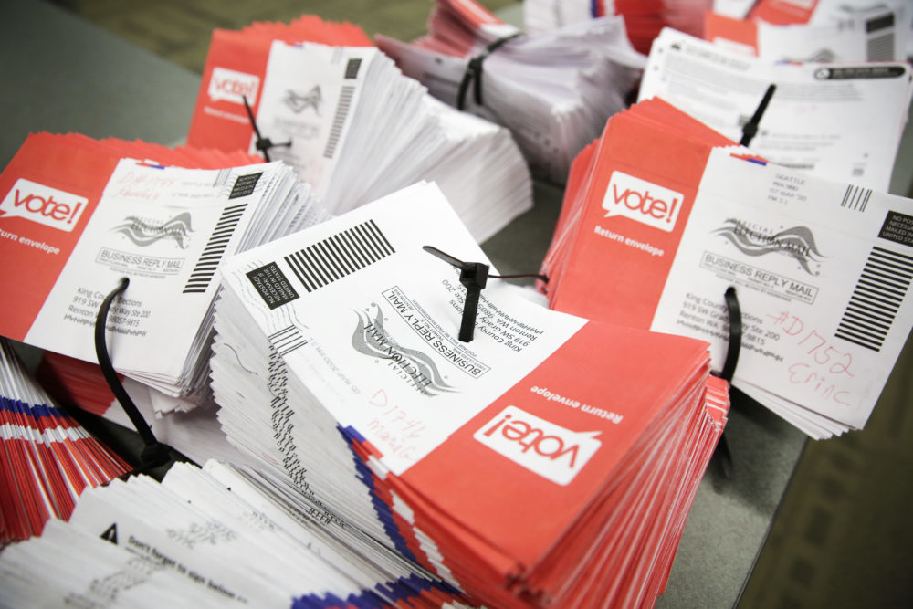 Stacks of mail-in votes sit together on a table.