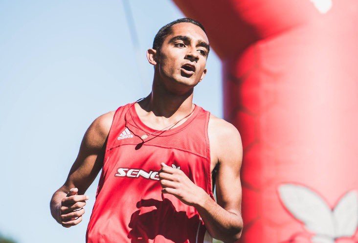 Aidan D'Souza is shown running while wearing a red Seneca jersey.